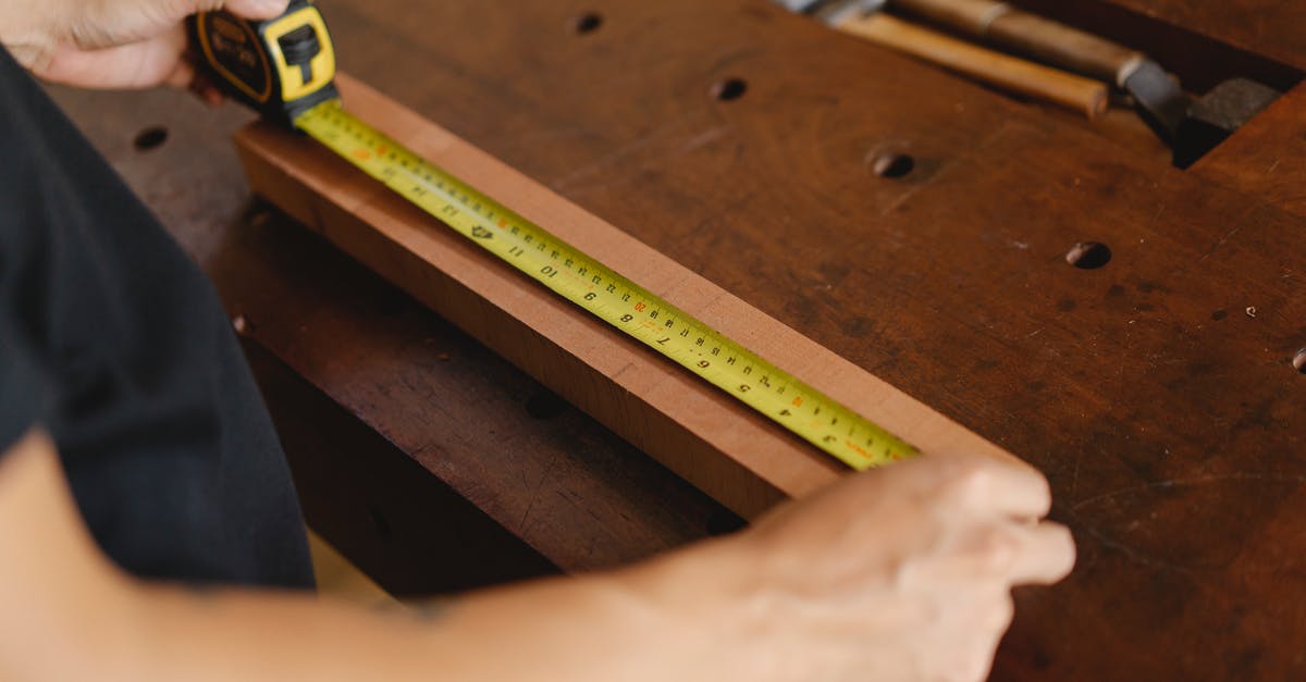 Royal icing - how important is accurate measuring? - Unrecognizable male carpenter standing at wooden workbench and measuring length of board with yellow tape measure while working in professional studio Royal icing - how important is accurate measuring? - Unrecognizable male carpenter standing at wooden workbench and measuring length of board with yellow tape measure while working in professional studio