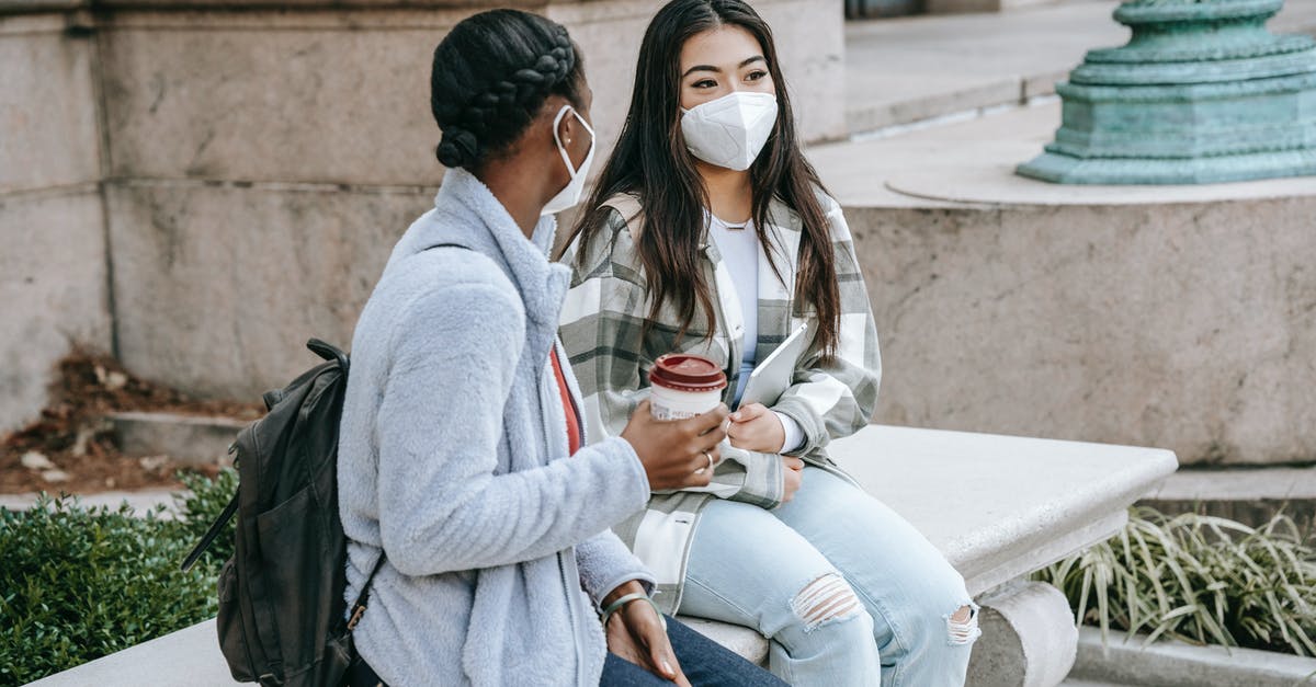 Safety of coffee in thermal flask, long periods of time - Multiethnic girlfriends sitting in street in masks Safety of coffee in thermal flask, long periods of time - Multiethnic girlfriends sitting in street in masks