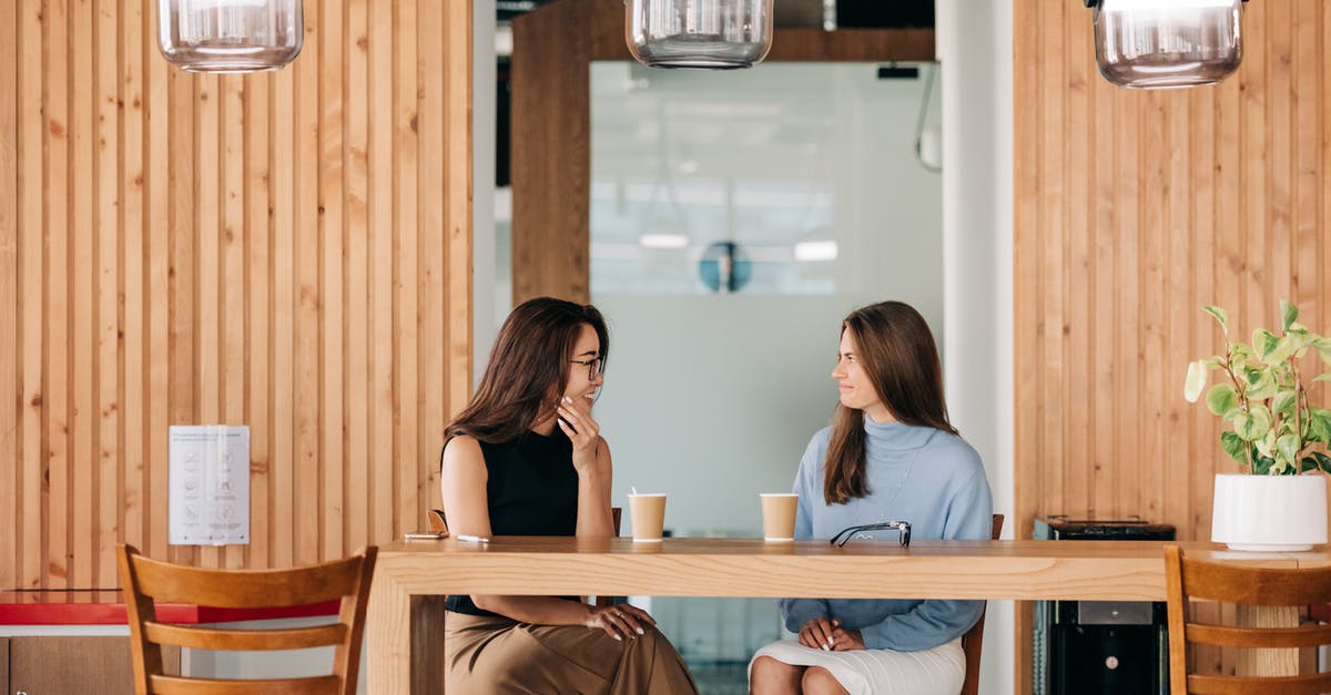 Safety of coffee in thermal flask, long periods of time - Cheerful diverse friends talking at table with coffee in cafe Safety of coffee in thermal flask, long periods of time - Cheerful diverse friends talking at table with coffee in cafe