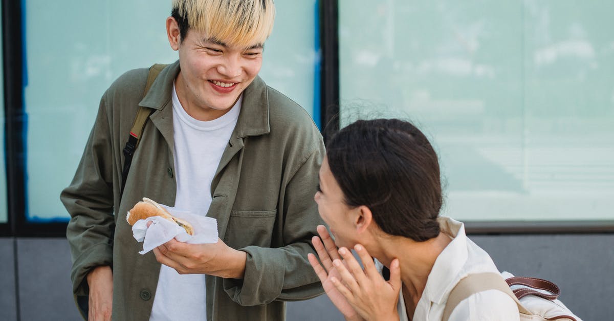 Sausage exploded and looks foamy - Joyful Asian couple enjoying hot dog on street Sausage exploded and looks foamy - Joyful Asian couple enjoying hot dog on street