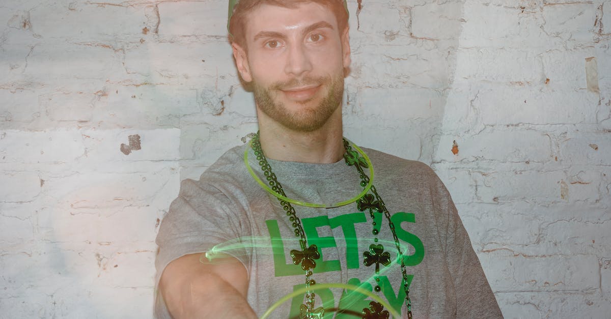 Saving a pavlova that didn't form a crust - Through glass wall view of friendly adult male in beads looking at camera while twirling plastic ring while celebrating Saint Patrics day Saving a pavlova that didn't form a crust - Through glass wall view of friendly adult male in beads looking at camera while twirling plastic ring while celebrating Saint Patrics day