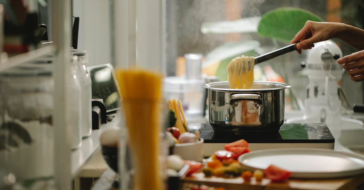 Saving pasta water - Crop anonymous housewife picking freshly cooked Italian spaghetti from saucepan while cooking and serving food in light kitchen Saving pasta water - Crop anonymous housewife picking freshly cooked Italian spaghetti from saucepan while cooking and serving food in light kitchen