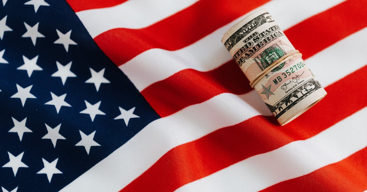 Saving spoiling mushrooms? - From above of United States currency folded in roll placed on USA flag illustrating concept of business profit and wealth Saving spoiling mushrooms? - From above of United States currency folded in roll placed on USA flag illustrating concept of business profit and wealth