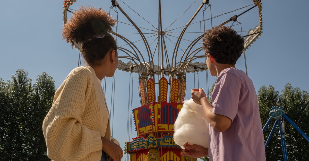 Savory Cotton Candy? - Teenage couple on date in amusement park looking at big carousel Savory Cotton Candy? - Teenage couple on date in amusement park looking at big carousel
