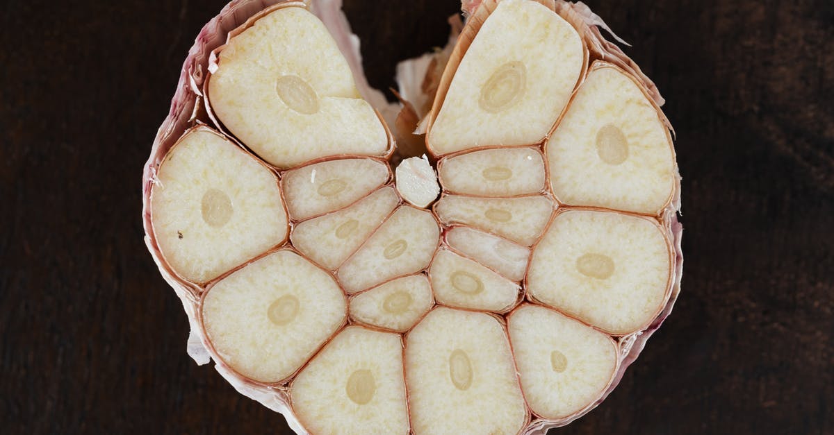 Scaling up a risotto recipe x4. Things to consider? - Bulb of ripe garlic in peel cut in half on wooden board Scaling up a risotto recipe x4. Things to consider? - Bulb of ripe garlic in peel cut in half on wooden board