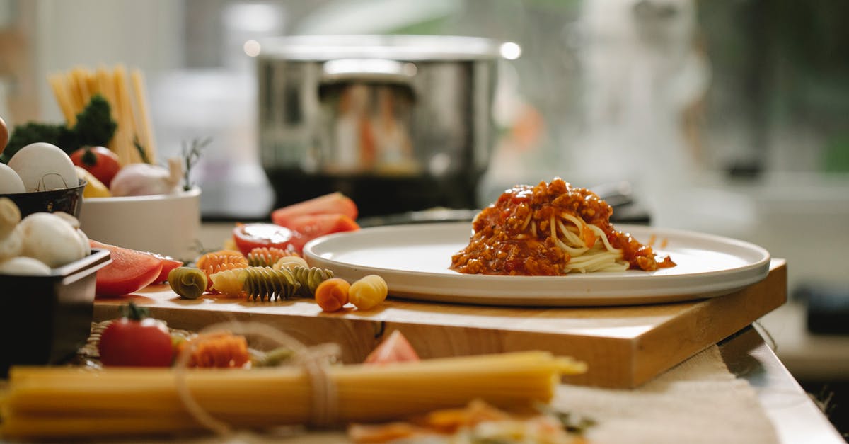 scratched ceramic pan - Appetizing homemade pasta with sauce on plate placed on wooden board in kitchen with different ingredients scratched ceramic pan - Appetizing homemade pasta with sauce on plate placed on wooden board in kitchen with different ingredients