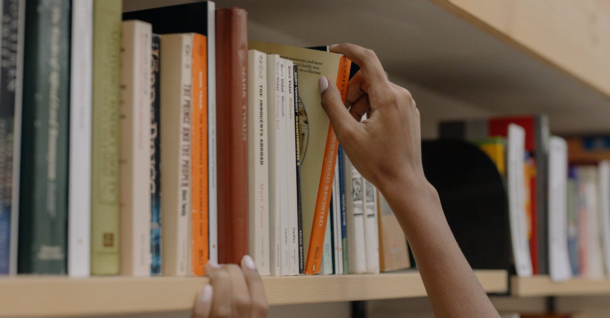 Selecting [corn] for Pozole? - Person Holding A Book On Wooden Shelf