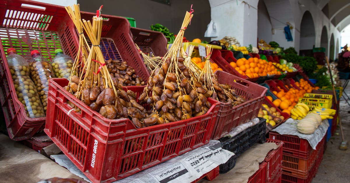 Sell by date of 4/17/19 - Stall of tasty heap of dates placed in box near various ripe fruits in local bazaar on street in city Sell by date of 4/17/19 - Stall of tasty heap of dates placed in box near various ripe fruits in local bazaar on street in city