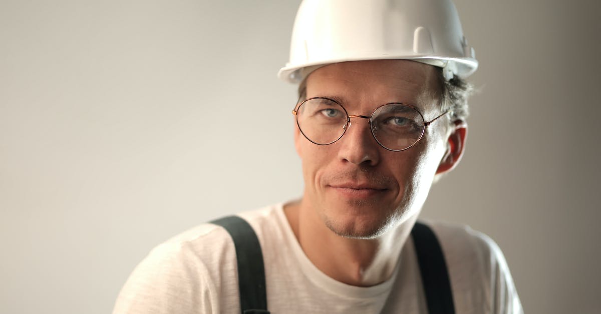 Separating Chlorophyll didn't work - Content male builder in workwear and hardhat smiling on gray background in studio and looking at camera