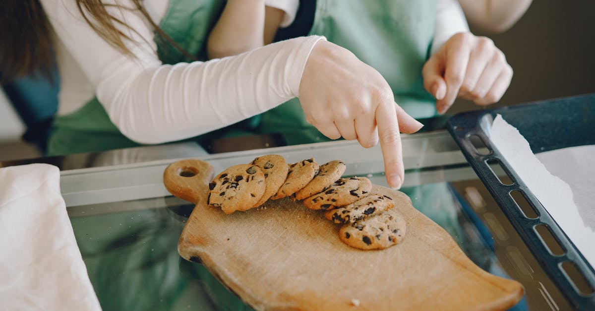 Separating chocolate-coated cookies stuck together - Crop woman and child with homemade cookies at home Separating chocolate-coated cookies stuck together - Crop woman and child with homemade cookies at home