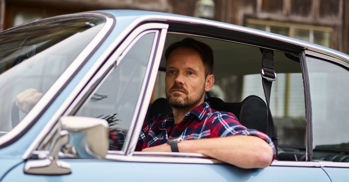 Shiny side or not for foil? - Adult thoughtful bearded driver in wristwatch and casual clothes driving blue automobile while passing by old building and looking away in daylight Shiny side or not for foil? - Adult thoughtful bearded driver in wristwatch and casual clothes driving blue automobile while passing by old building and looking away in daylight