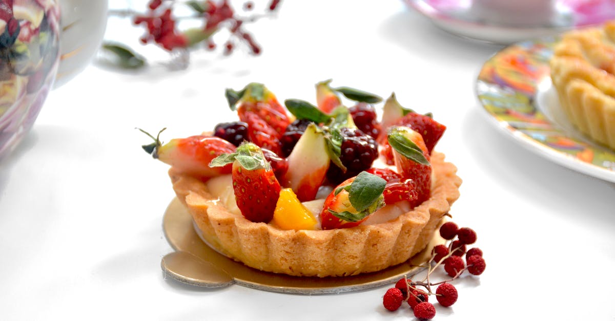 Shortcrust tart stopped working - Tasty tarlet decorated with ripe strawberries on table with fresh berries near tea set on blurred background in light kitchen Shortcrust tart stopped working - Tasty tarlet decorated with ripe strawberries on table with fresh berries near tea set on blurred background in light kitchen