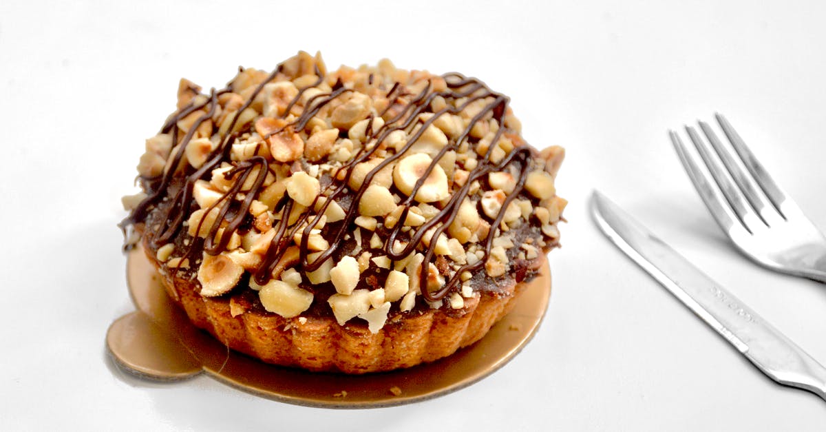 Shortcrust tart stopped working - Appetizing sweet pie tart with shortcrust pastry and chopped nuts topped with chocolate sauce on white background near fork and knife Shortcrust tart stopped working - Appetizing sweet pie tart with shortcrust pastry and chopped nuts topped with chocolate sauce on white background near fork and knife