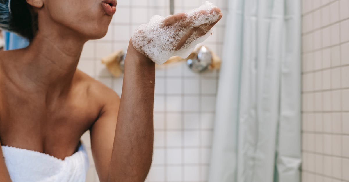 Should I remove the foam when cooking chickpeas? - Side view of crop anonymous African American female in towel blowing off foam from hand in bathroom