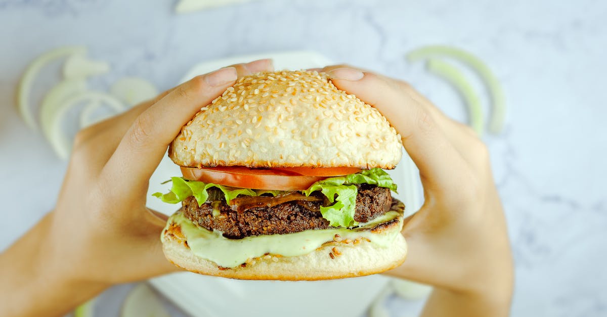 Should Pickle Slices be Above or Below the Hamburger - Anonymous person eating hamburger with cutlet and fresh vegetables Should Pickle Slices be Above or Below the Hamburger - Anonymous person eating hamburger with cutlet and fresh vegetables