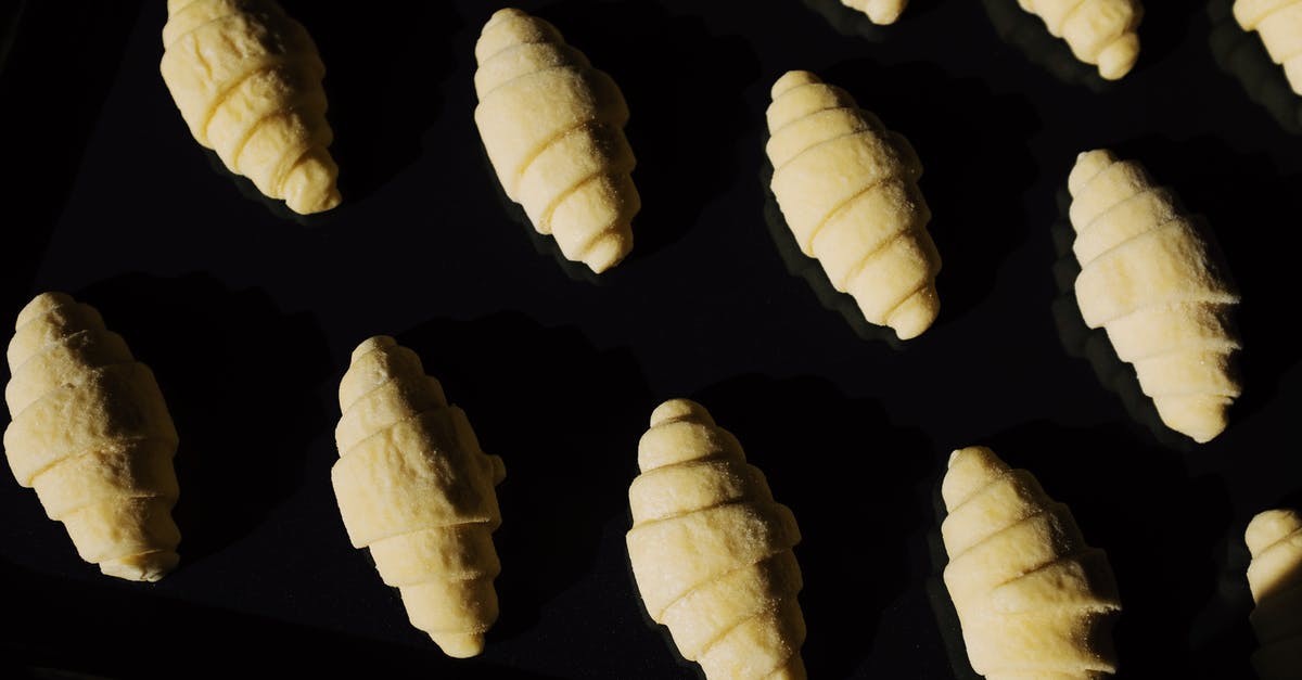 Simple Puff Pastry Dough - Top view composition of uncooked raw croissant dough arranged on surface of black glass in dark light Simple Puff Pastry Dough - Top view composition of uncooked raw croissant dough arranged on surface of black glass in dark light