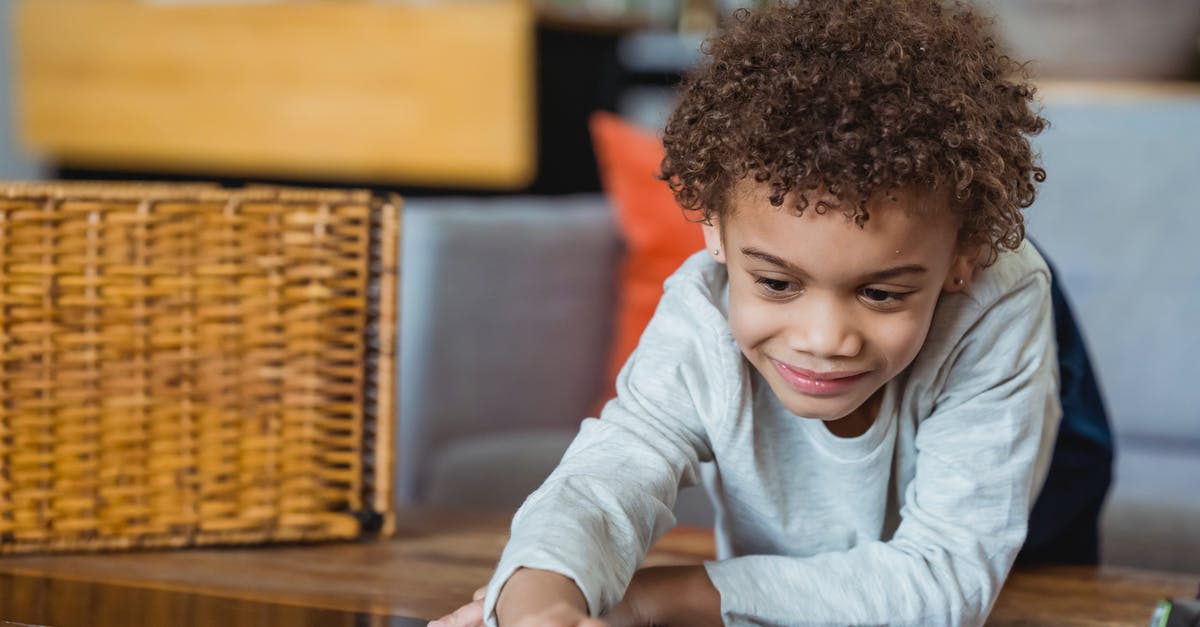 Small baskets for fries - Ethnic child in casual clothes leaning forward table and touching surface and looking down Small baskets for fries - Ethnic child in casual clothes leaning forward table and touching surface and looking down
