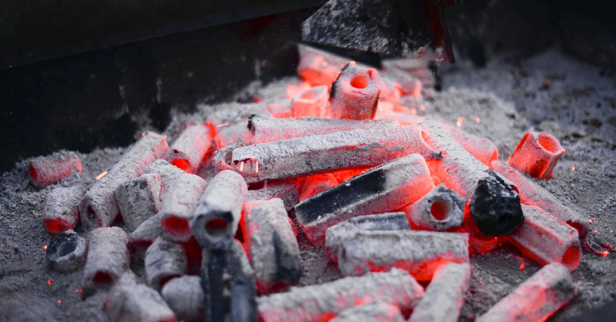 Small charcoal grill - raise fire grill? - Small hexagonal coals with holes smoldering on metal rack before roasting barbecue in nature Small charcoal grill - raise fire grill? - Small hexagonal coals with holes smoldering on metal rack before roasting barbecue in nature