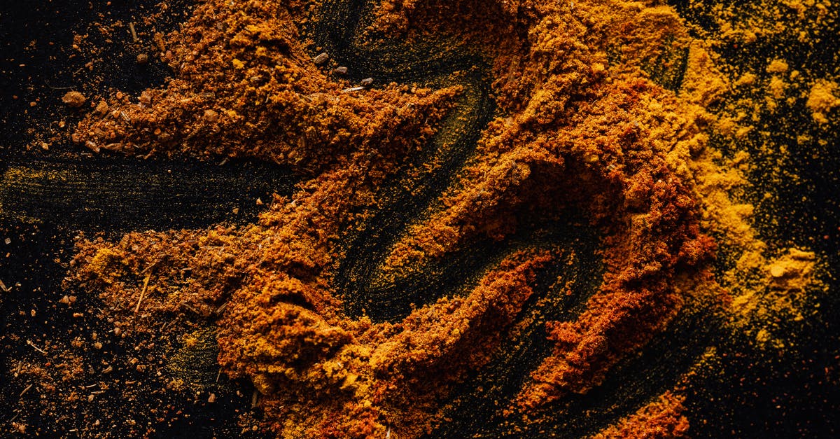 Soft bones in smoked chicken - From above of creative design of smoked ground paprika and turmeric mixed together on black surface Soft bones in smoked chicken - From above of creative design of smoked ground paprika and turmeric mixed together on black surface