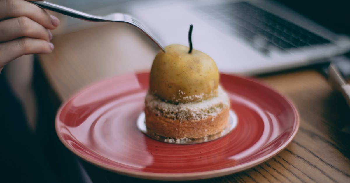 Sour cream peach pecan pie - Crop anonymous female with fork enjoying yummy fresh peach dessert while sitting at table with laptop Sour cream peach pecan pie - Crop anonymous female with fork enjoying yummy fresh peach dessert while sitting at table with laptop