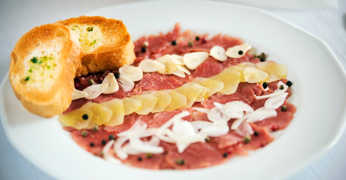 Sourdough Starter Black Spots - Tasty appetizer of carpaccio with raw onion and ginger slices with black peppercorns on plate in restaurant on white background Sourdough Starter Black Spots - Tasty appetizer of carpaccio with raw onion and ginger slices with black peppercorns on plate in restaurant on white background
