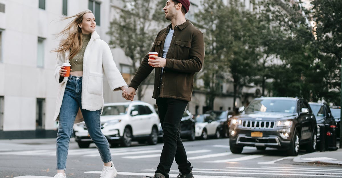 Sourdough teacakes/hot cross buns? - Young couple wearing warm jackets and with paper cups of hot drinks crossing road holding hands and looking at each other Sourdough teacakes/hot cross buns? - Young couple wearing warm jackets and with paper cups of hot drinks crossing road holding hands and looking at each other