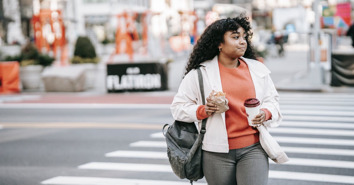Sourdough teacakes/hot cross buns? - Friendly black woman with takeaway coffee crossing road in city Sourdough teacakes/hot cross buns? - Friendly black woman with takeaway coffee crossing road in city