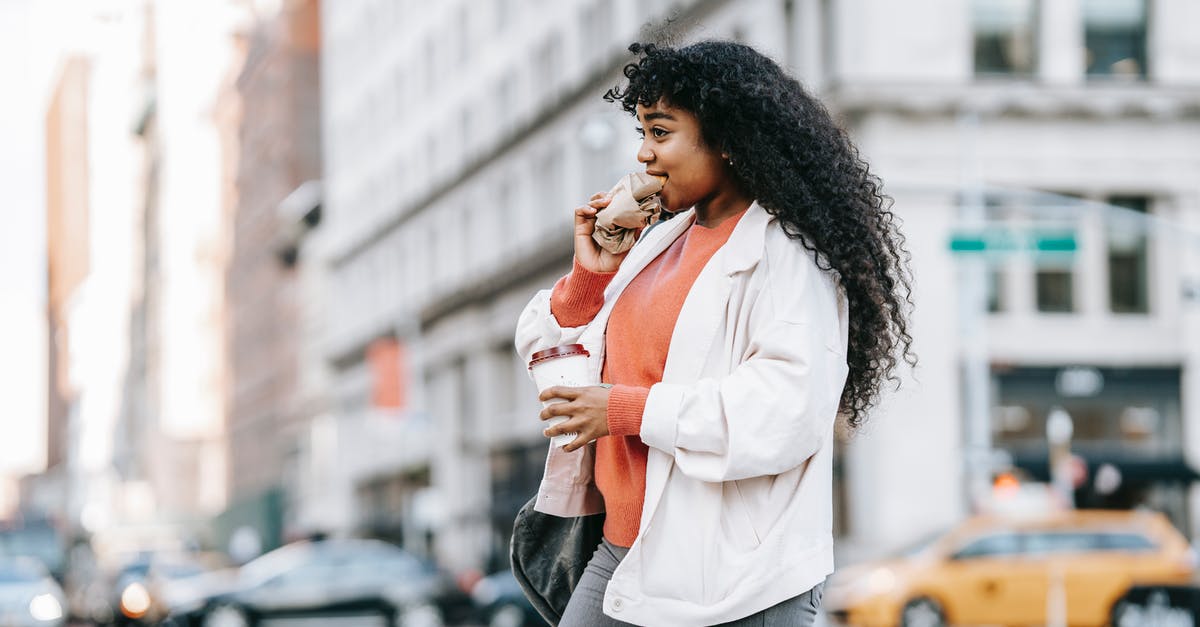 Sourdough teacakes/hot cross buns? - Black woman biting sandwich and crossing road Sourdough teacakes/hot cross buns? - Black woman biting sandwich and crossing road