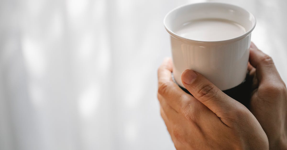 soy milk production with no beany flavor - Crop faceless person holding cup of hot milk