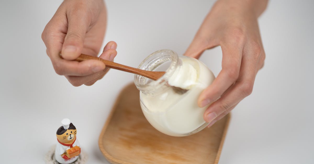 soy milk production with no beany flavor - Crop man taking natural yogurt with spoon from jar