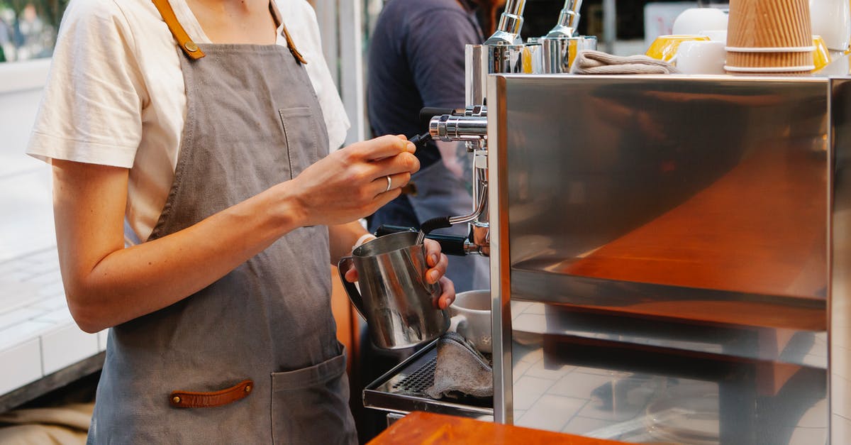 Special coffee served in Malaysia (or India) - Crop anonymous female in apron making hot coffee with special coffee machine in kitchen of cafe Special coffee served in Malaysia (or India) - Crop anonymous female in apron making hot coffee with special coffee machine in kitchen of cafe