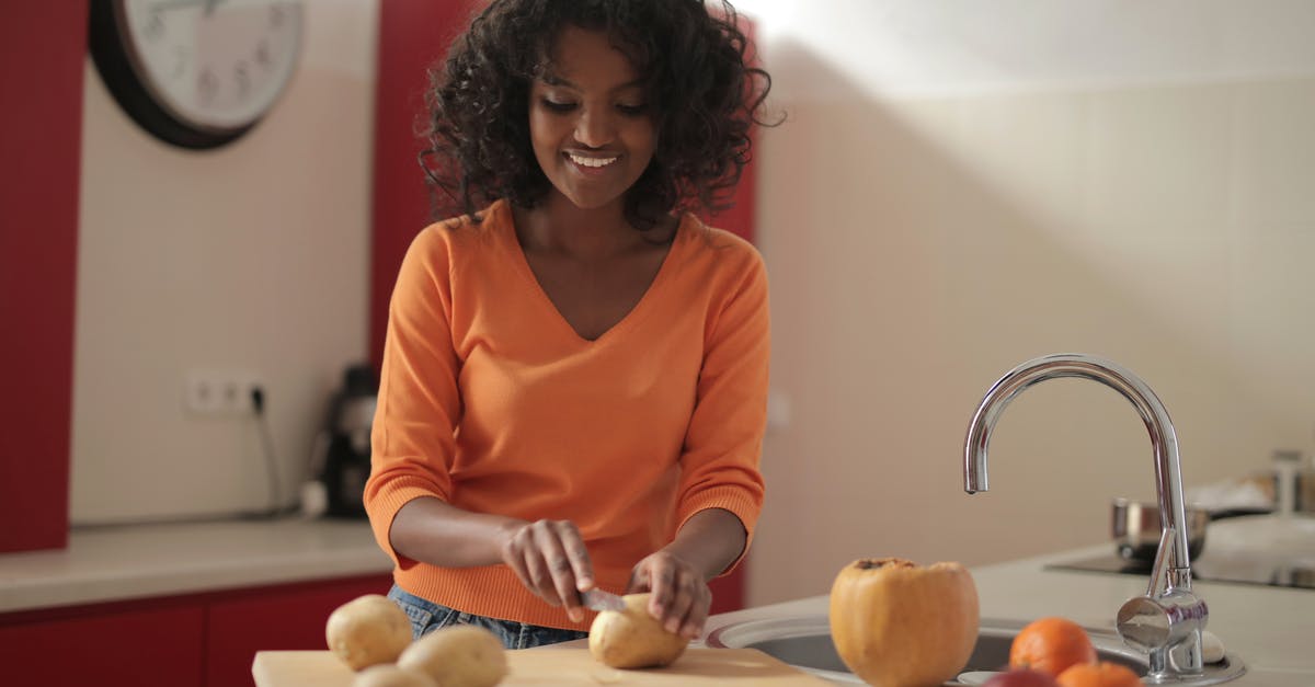 Starch Content of Dehydrated Potatoes - Cheerful woman cutting potatoes in kitchen Starch Content of Dehydrated Potatoes - Cheerful woman cutting potatoes in kitchen