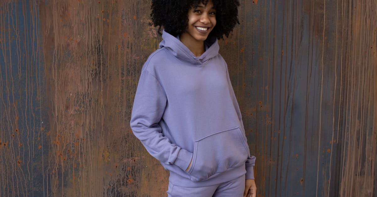 Steaks look light brown aren't charing - Positive young African American female in purple hoodie and pants standing near brown wall and looking at camera in light place Steaks look light brown aren't charing - Positive young African American female in purple hoodie and pants standing near brown wall and looking at camera in light place