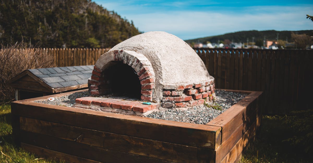 Storing Pizza Stone in Oven - Aged outdoor pizza oven on wooden construction on grass behind mountains under blue cloudy sky Storing Pizza Stone in Oven - Aged outdoor pizza oven on wooden construction on grass behind mountains under blue cloudy sky