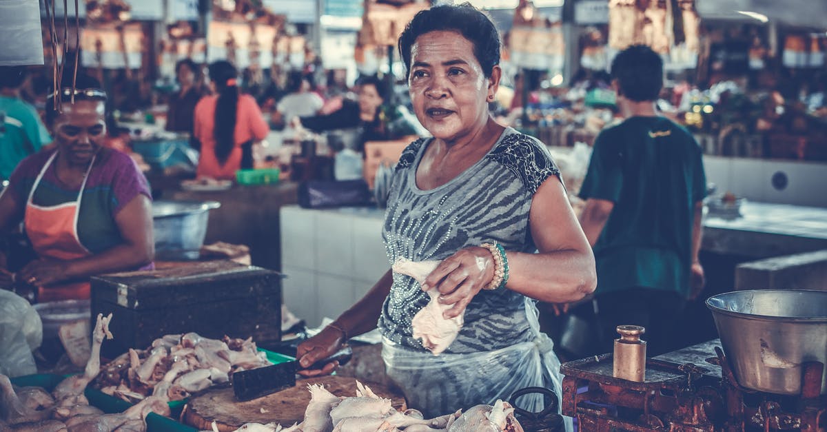 Storing spoiled meat with fresh meat in a freezer - Woman in Gray Shirt Holding a Chicken Piece Storing spoiled meat with fresh meat in a freezer - Woman in Gray Shirt Holding a Chicken Piece