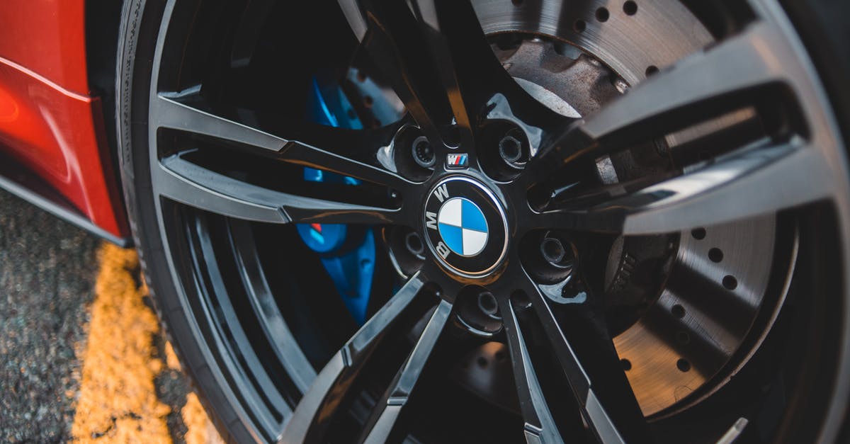 Storing/transporting nut brittle in tins - From above modern red auto wheel metal rim with shiny lug nuts on asphalt road with marking line Storing/transporting nut brittle in tins - From above modern red auto wheel metal rim with shiny lug nuts on asphalt road with marking line