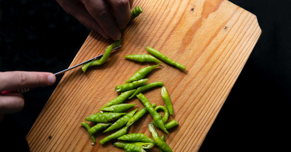 Substitute Cayenne Pepper for Black Pepper - Top view of crop anonymous person cutting fresh green chili peppers on wooden chopping board Substitute Cayenne Pepper for Black Pepper - Top view of crop anonymous person cutting fresh green chili peppers on wooden chopping board