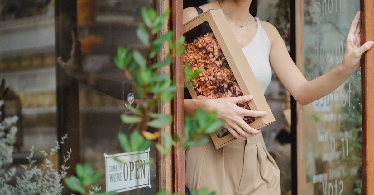 Substitute dried pig's blood for fresh - Crop glad woman with dried flowers box leaving floristry store Substitute dried pig's blood for fresh - Crop glad woman with dried flowers box leaving floristry store