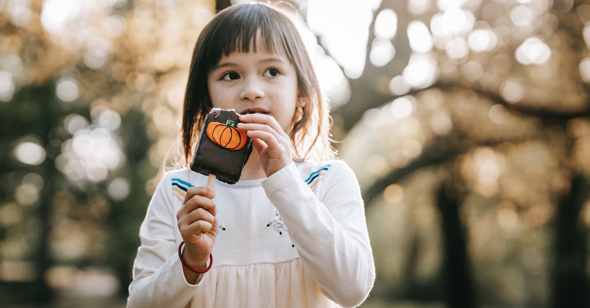 Substituting white chocolate in Julia Child's mousse - Adorable little girl in white clothes standing in park with bitten tasty chocolate Halloween sweet on stick and looking away Substituting white chocolate in Julia Child's mousse - Adorable little girl in white clothes standing in park with bitten tasty chocolate Halloween sweet on stick and looking away