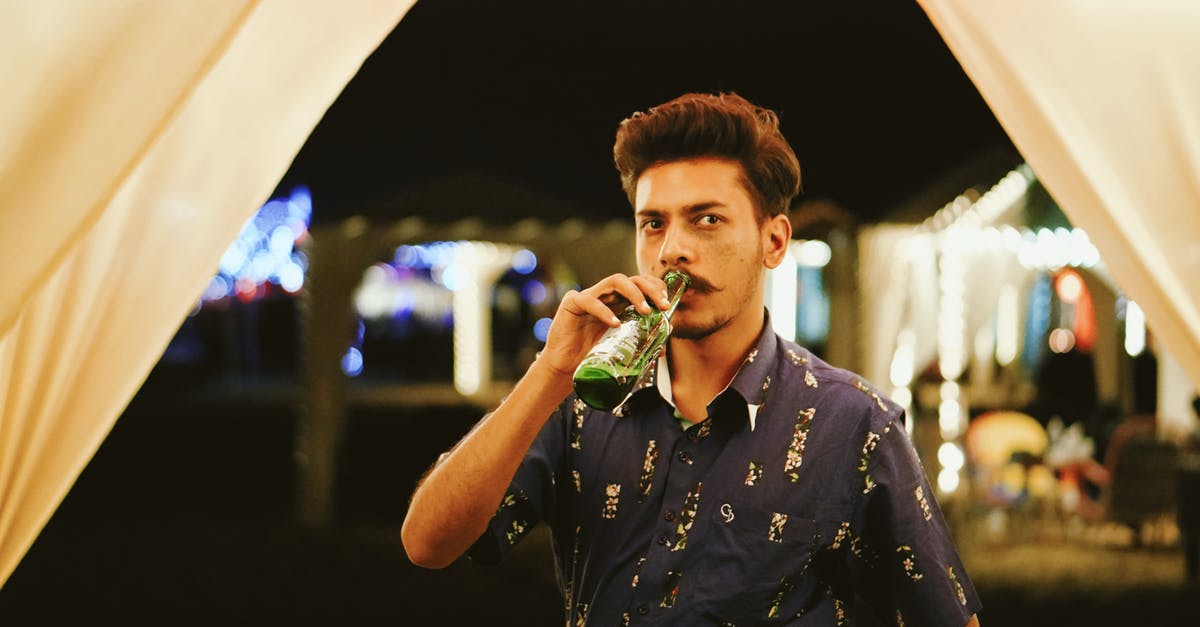 Substitution of root beer concentrate for extract - Stylish young ethnic bearded mail in casual outfit drinking bottle of beer and looking at camera while relaxing in outdoor bar at night Substitution of root beer concentrate for extract - Stylish young ethnic bearded mail in casual outfit drinking bottle of beer and looking at camera while relaxing in outdoor bar at night