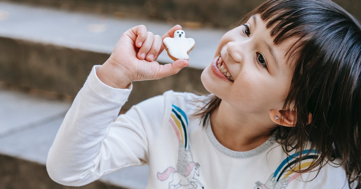 Sugar content of food - Adorable smiling girl with cookie made for Halloween holiday sitting on stone stairs Sugar content of food - Adorable smiling girl with cookie made for Halloween holiday sitting on stone stairs