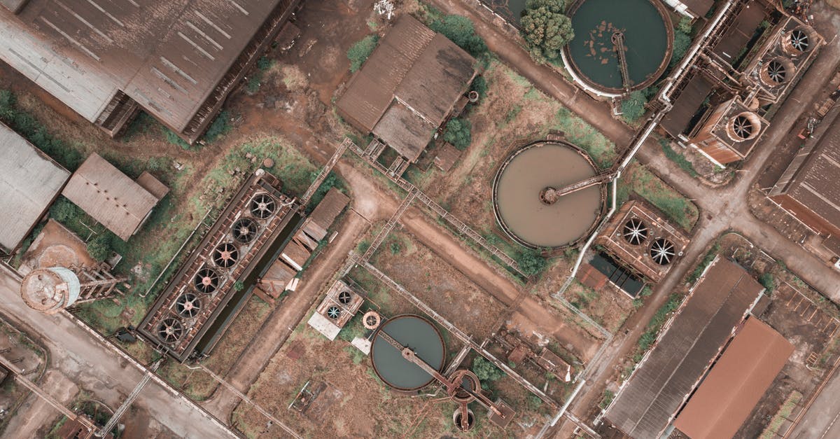Supply of Boiling water without power outlet - Drone view of shabby factory with round settling tanks with mechanical means removing solids in water treatment plant Supply of Boiling water without power outlet - Drone view of shabby factory with round settling tanks with mechanical means removing solids in water treatment plant