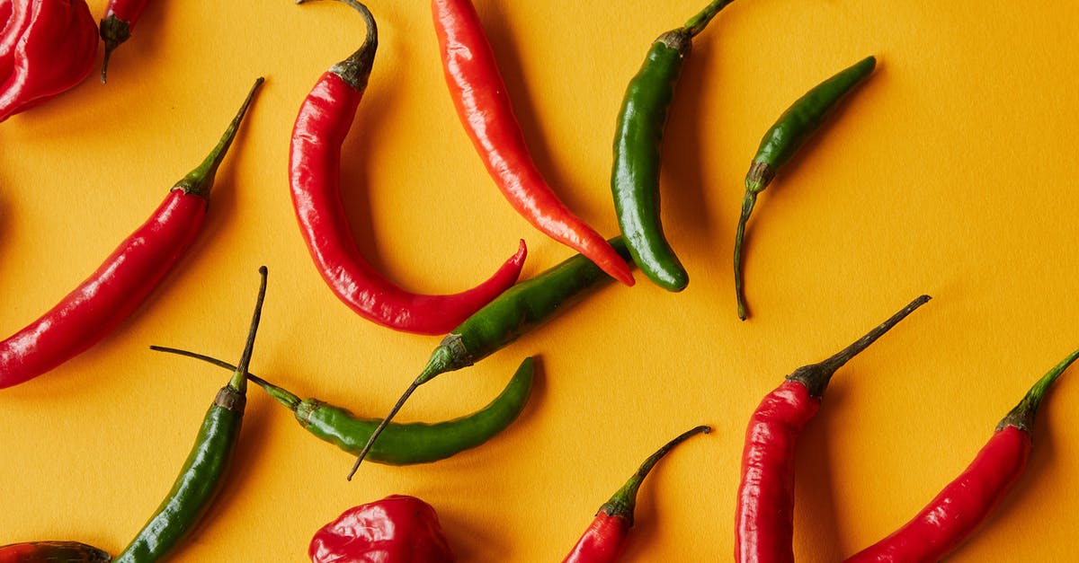 Tasting food in kitchen - Red and green peppers on yellow background Tasting food in kitchen - Red and green peppers on yellow background