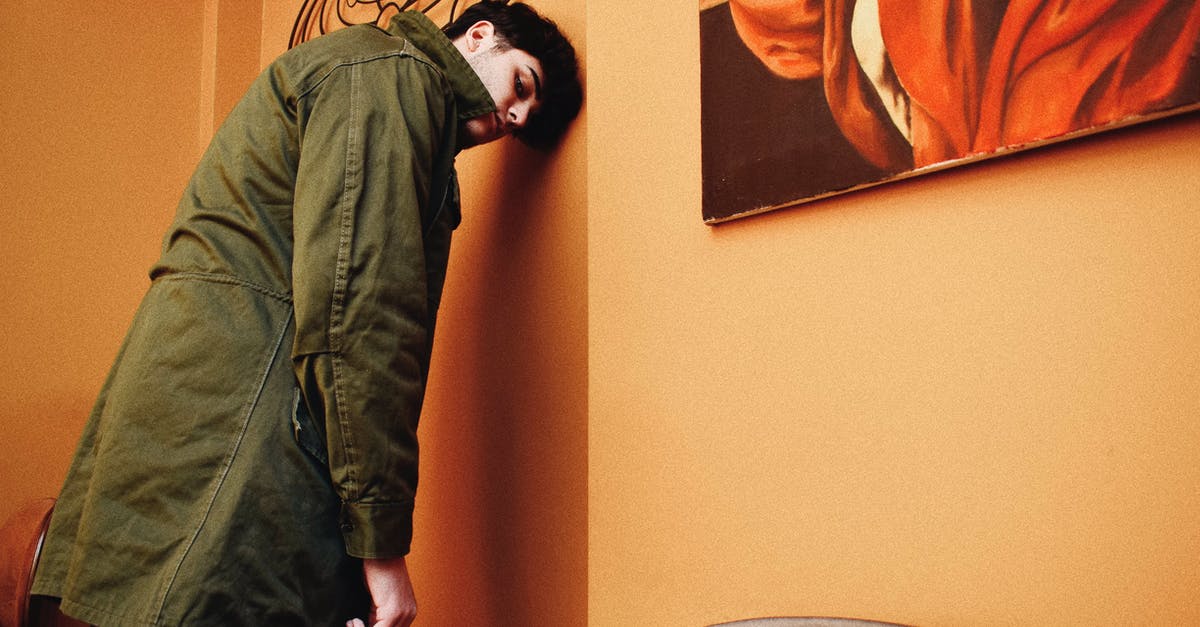 Technical reasons against chocolate-coated shortbread - Young Man in Coat Leaning His Forehead Against Wall in Cafeteria Technical reasons against chocolate-coated shortbread - Young Man in Coat Leaning His Forehead Against Wall in Cafeteria