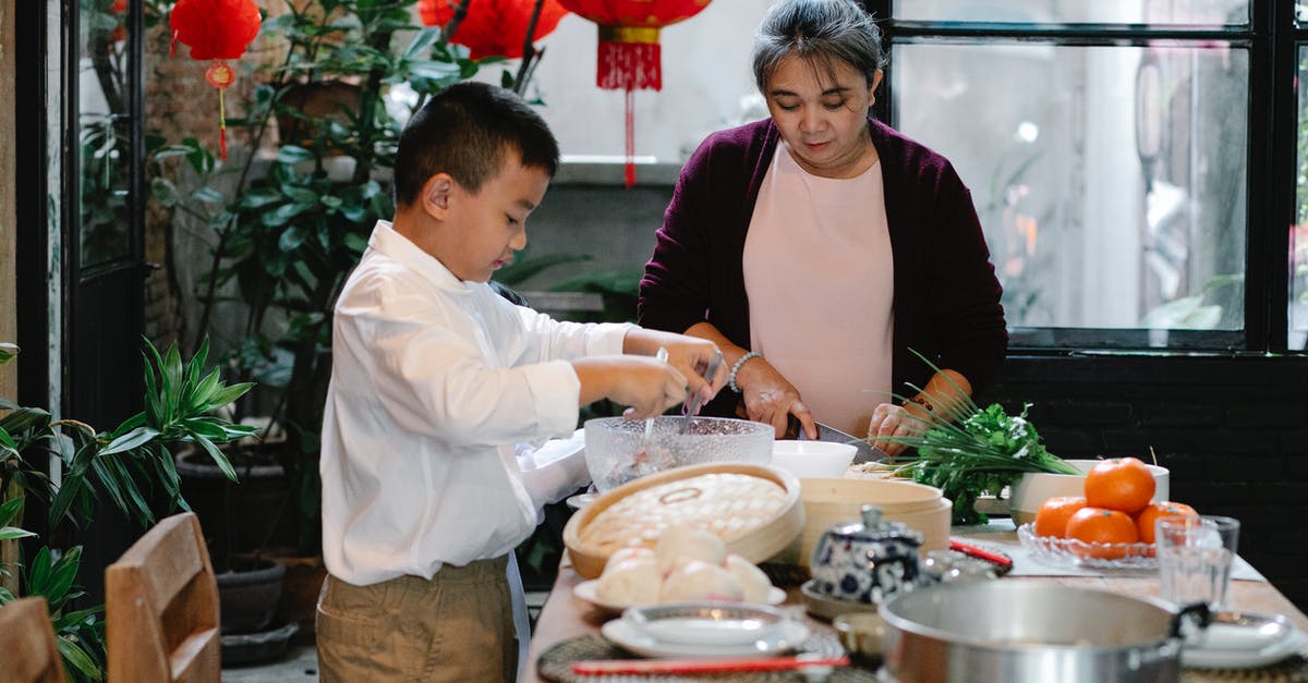 Techniques for mixing bread dough with stand mixer - Focused ethnic boy mixing ingredients for stuffing for cooking traditional Chinese dumplings with granny at kitchen