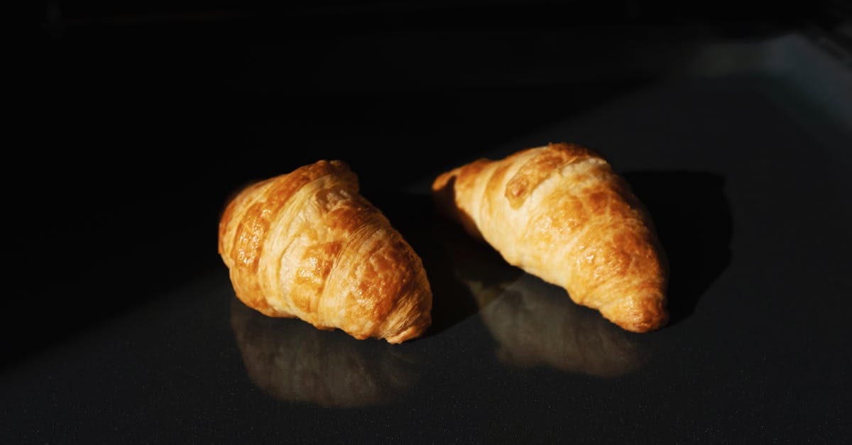 Techniques to get a nice golden-brown crust on bread - Pair of fresh yummy croissants on black glass surface Techniques to get a nice golden-brown crust on bread - Pair of fresh yummy croissants on black glass surface