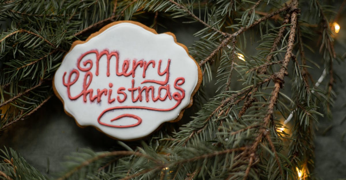 Thin chutney batch from a year ago - From above of yummy gingerbread cookie with inscription on sugar glaze between spruce sprigs with shiny garland during New Year holiday Thin chutney batch from a year ago - From above of yummy gingerbread cookie with inscription on sugar glaze between spruce sprigs with shiny garland during New Year holiday