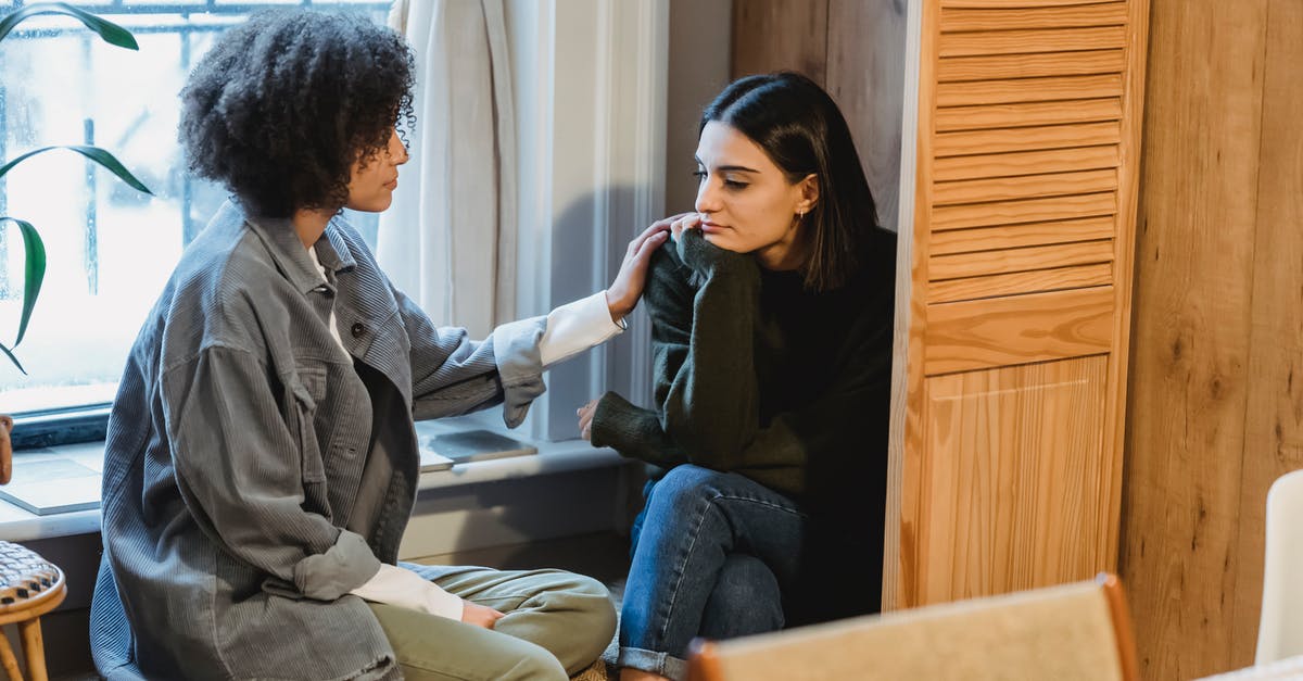 Timing problem! [duplicate] - Calm young multiracial female best friends in casual clothes sitting near window and home and discussing discussing problems