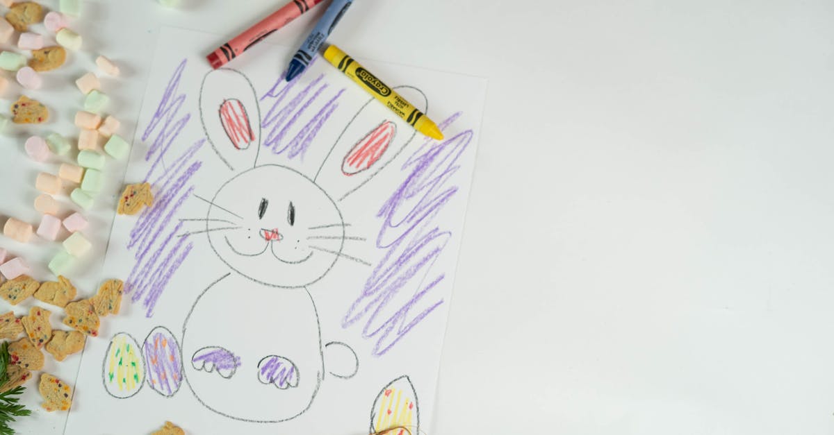 tiny quantity of egg in a cookie - Top view of colorful crayons and picture of bunny and eggs placed on white background with marshmallows and cookies during Easter holiday tiny quantity of egg in a cookie - Top view of colorful crayons and picture of bunny and eggs placed on white background with marshmallows and cookies during Easter holiday