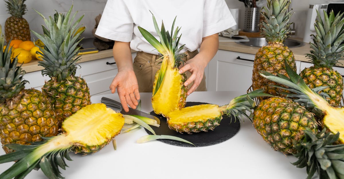 Tips for cooked chicken to stay juicy half a day - Crop unrecognizable cook demonstrating cut ripe pineapples with green leaves in kitchen